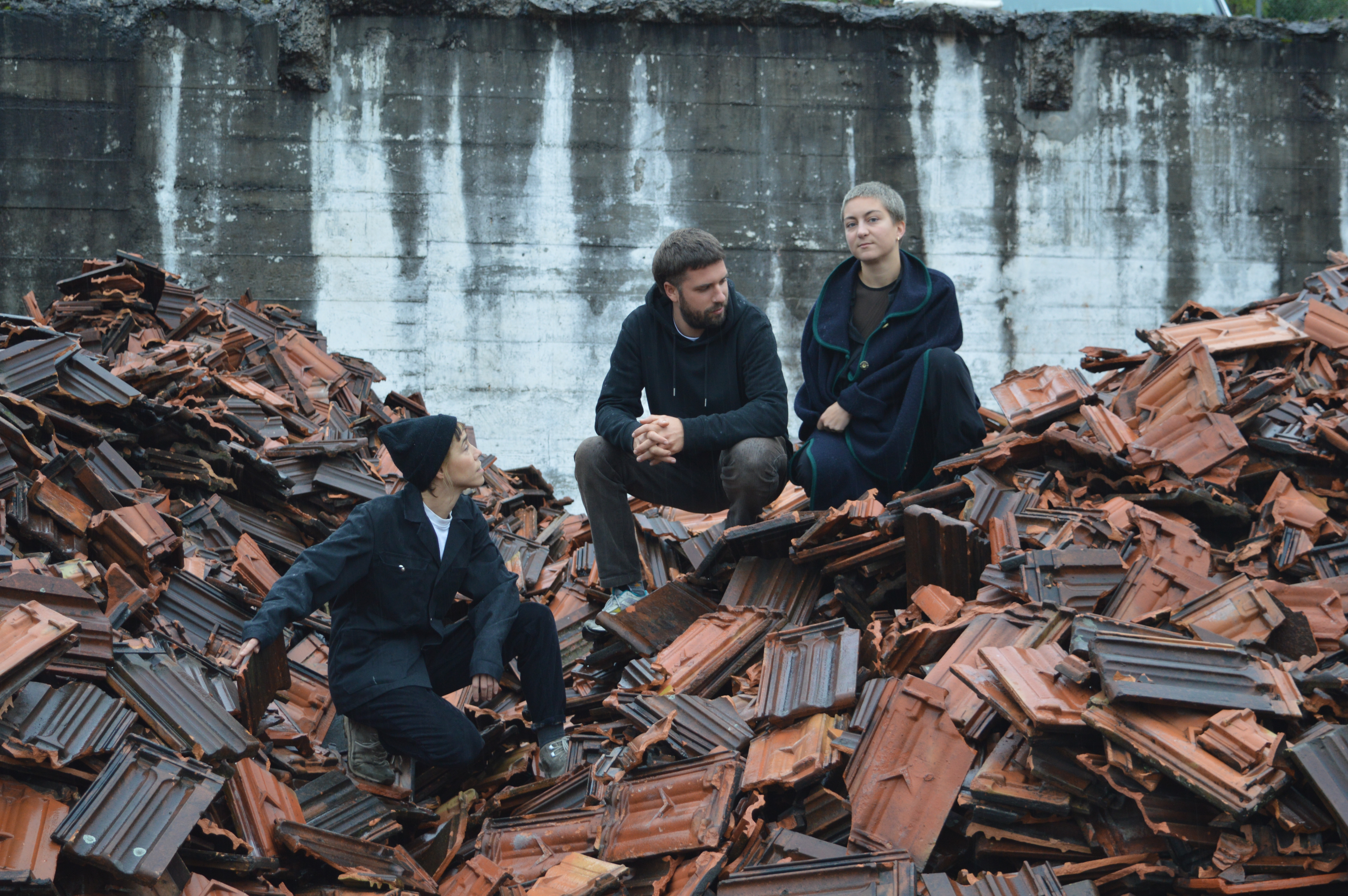 drei personen auf einem haufen zerbrochener dachziegel.