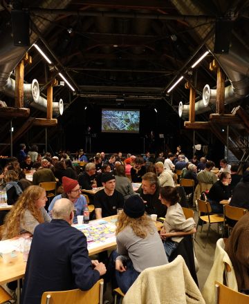 Im grossen Saal in der Schüür gab es drei Tischreihen, an denen verschiedene Leute sitzen. 