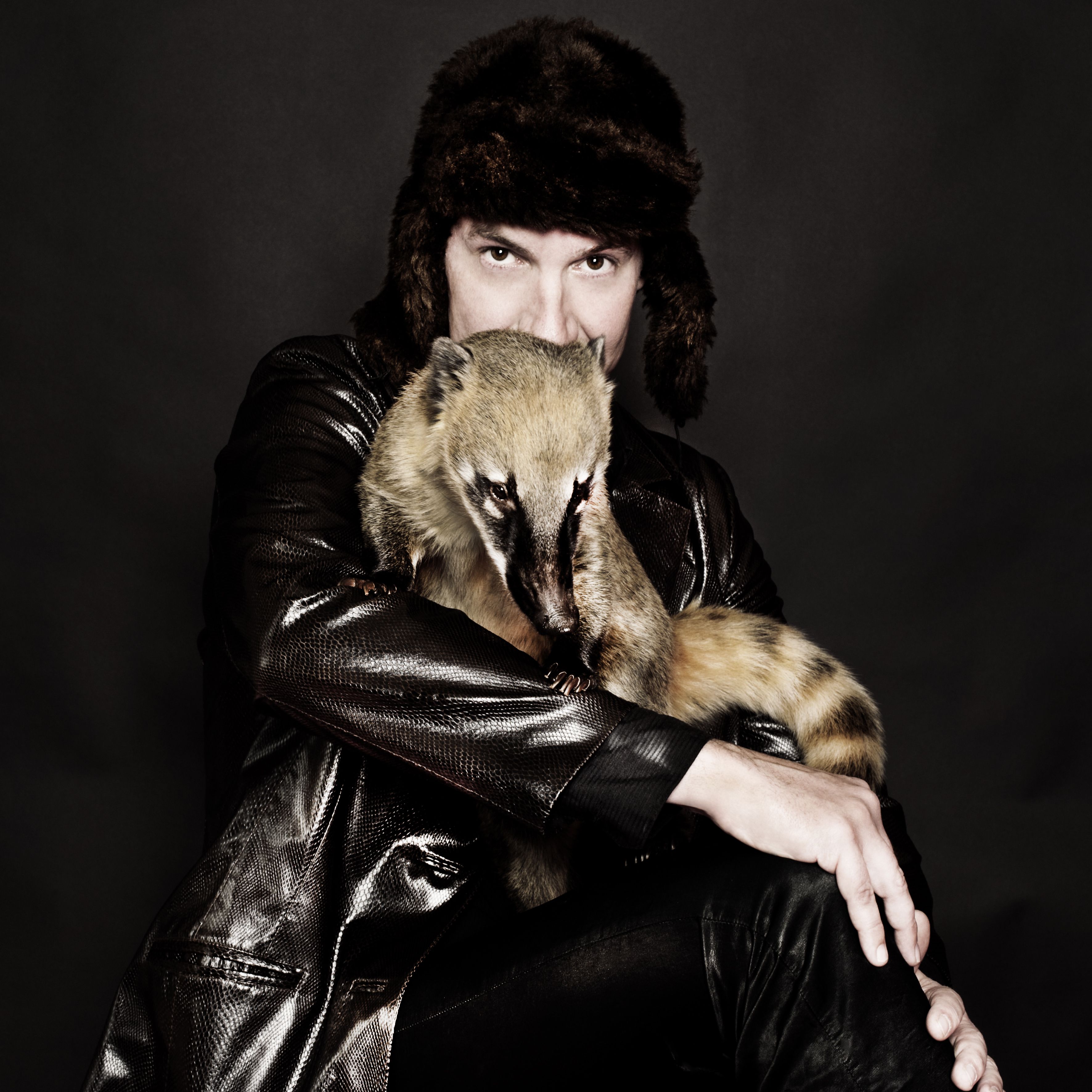 Ein Mann mit Pelzkappe und einem Tir auf seinem Schoss.