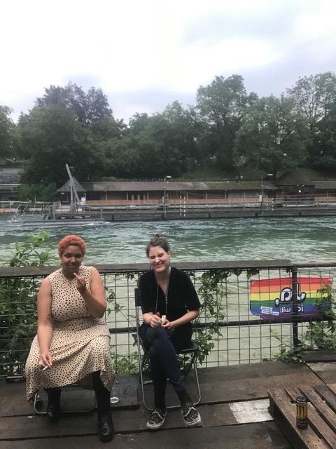 Zwei Menschen sitzen auf einem Stuhl an einem Fluss.