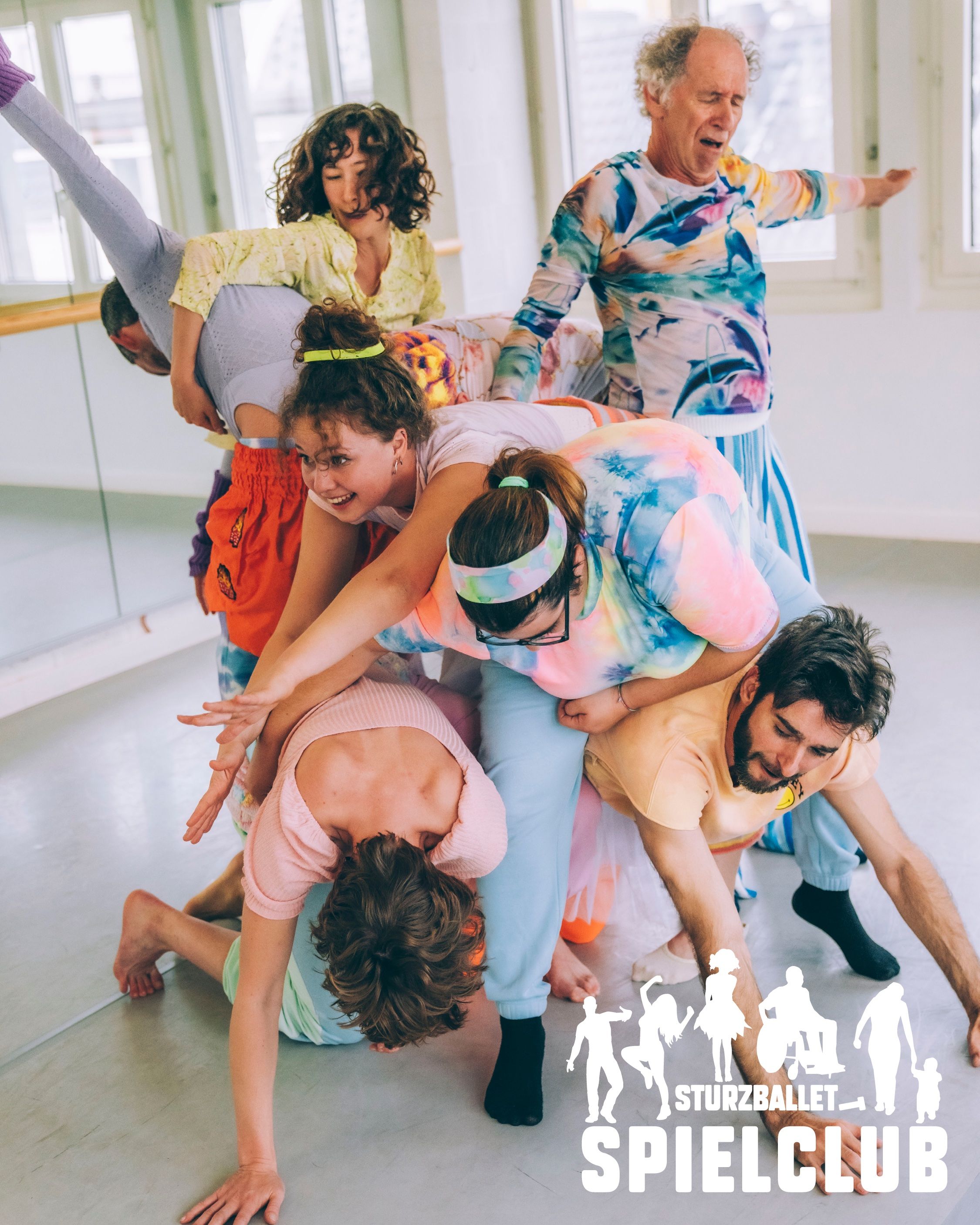 Mehrer Menschen in Gymnastikoutfits stehen vor einem Spiegel übereinander. Sie lieg quasi aufeinander und sind ein wenig ineinader verkeilt.