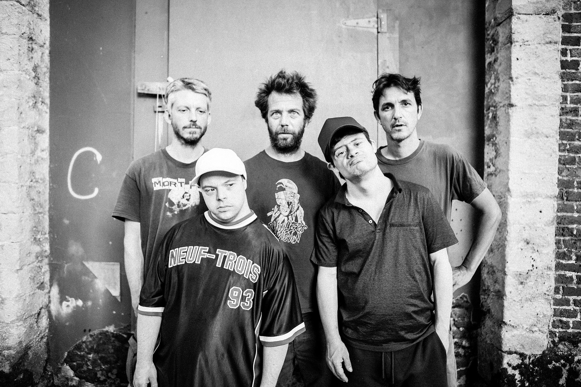 Schwarzweissfoto von fünf Männern, ein Mann im Vordergrund mit heller Kappe hat Down Syndrom.