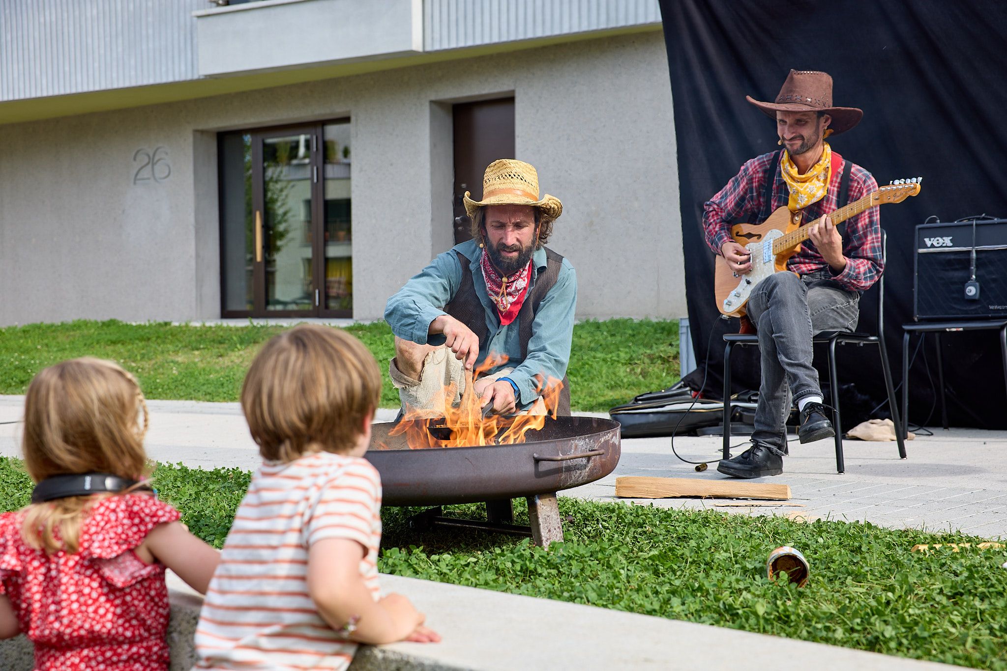 zwei Cowboys machen Feuer, einer spielt dabei Gitarre