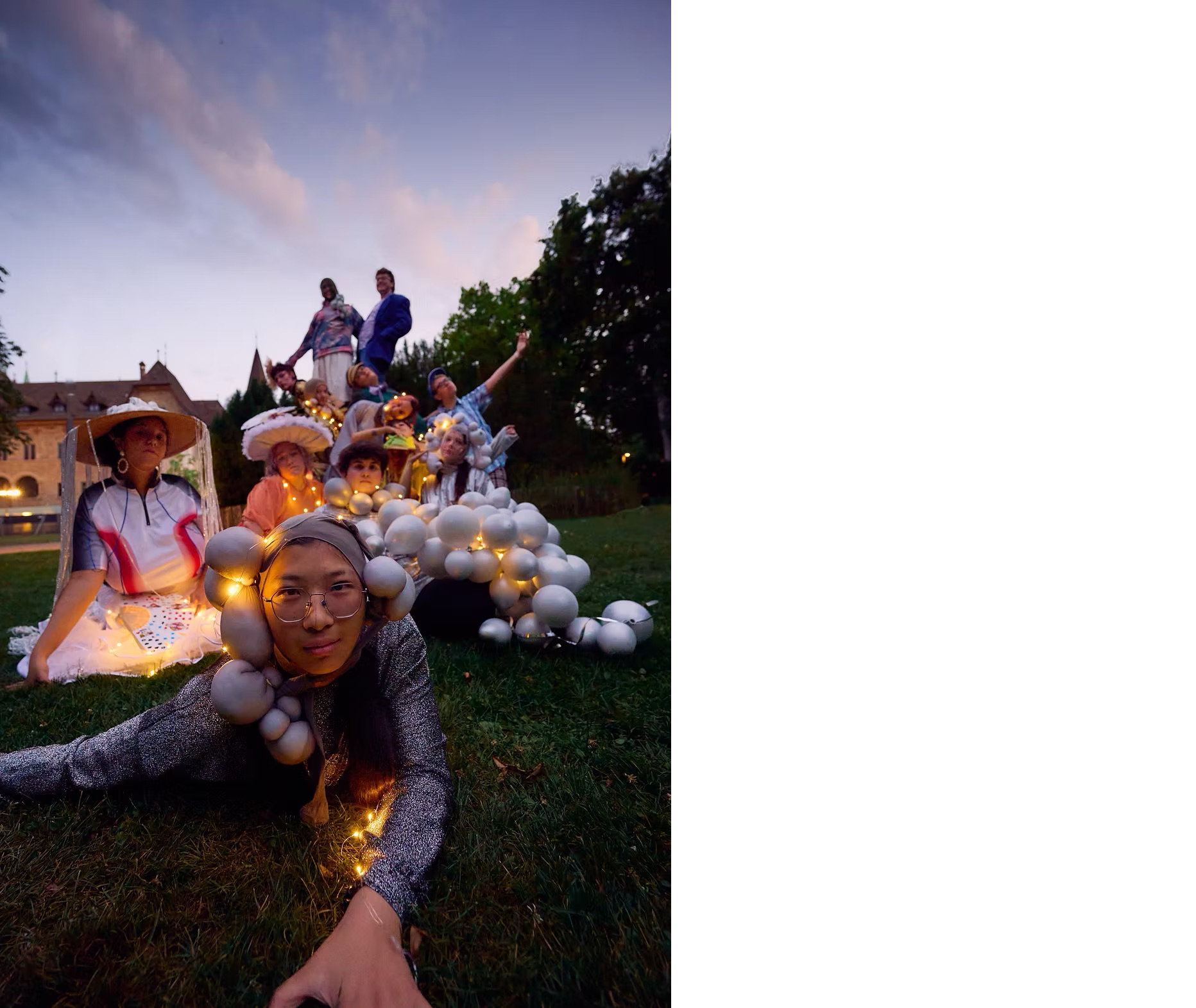 Eine Gruppe Menschen, bunt verkleidet auf einer Wiese. Einige Tragen extravagente Kostüme.