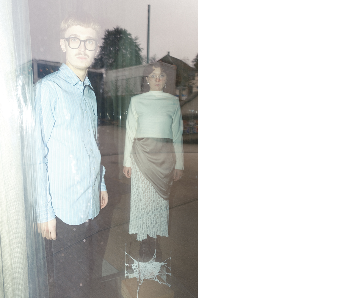 Zwei Personen hinter einer Glasscheibe fotografiert.